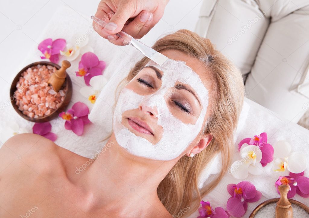 Cosmetician Applying Facial Mask On Face Of Woman